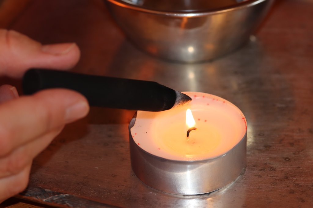 Die Moxakohle wird über einer Kerze erwärmt